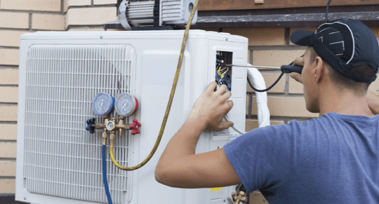 Man outside repairing a heat pump