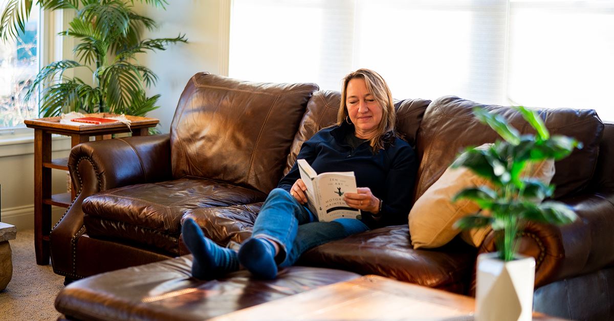 woman sitting on couch reading a book