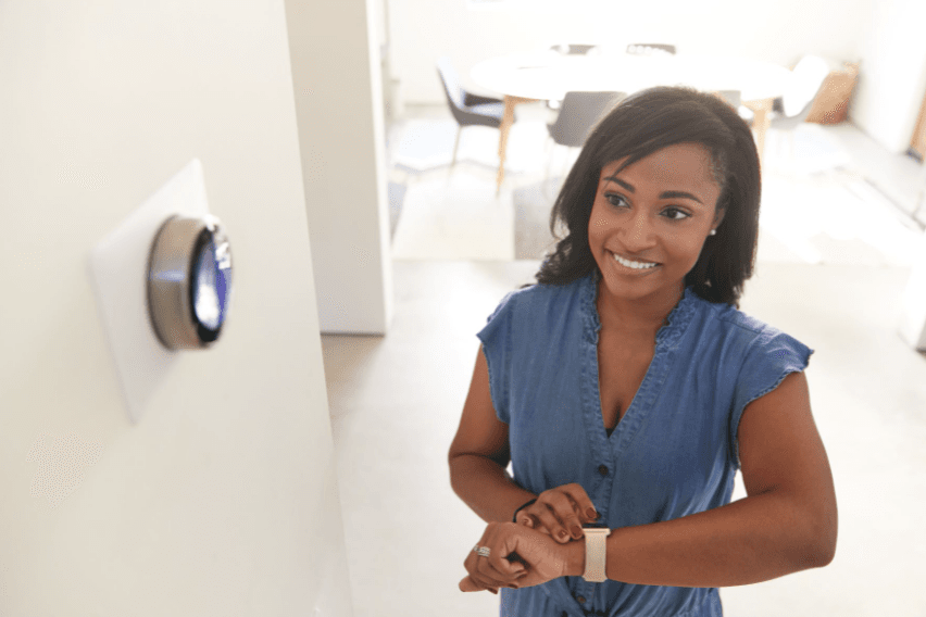 Women with a smart watch in front of a smart thermostat